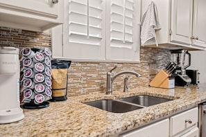 A kitchen with a granite countertop, a coffee maker, a bag of coffee, a knife block, and a blender. - Nordic-Inspired Getaway | Hot Tub + Fire Pit (North Richland Hills)