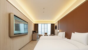 Una habitación de hotel con una cama grande, un escritorio, una silla, un televisor montado en la pared y una ventana con cortinas.