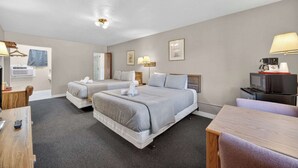 A hotel room with two beds, a desk, a chair, a TV, and a microwave. - Eagle Motel Suite 105 (Manitou Springs)