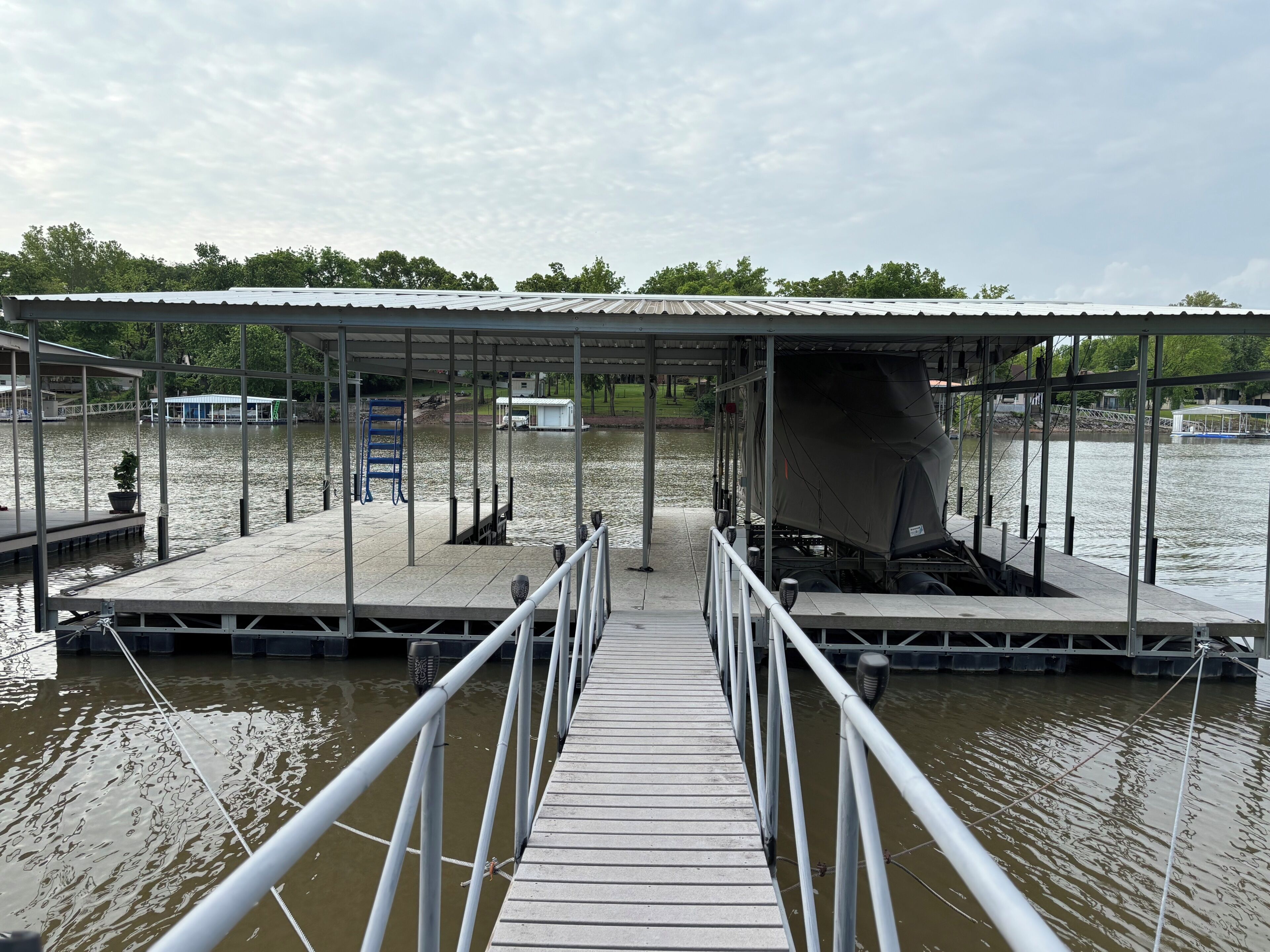 A pier leading to a covered dock area with a boat and a covered vehicle.