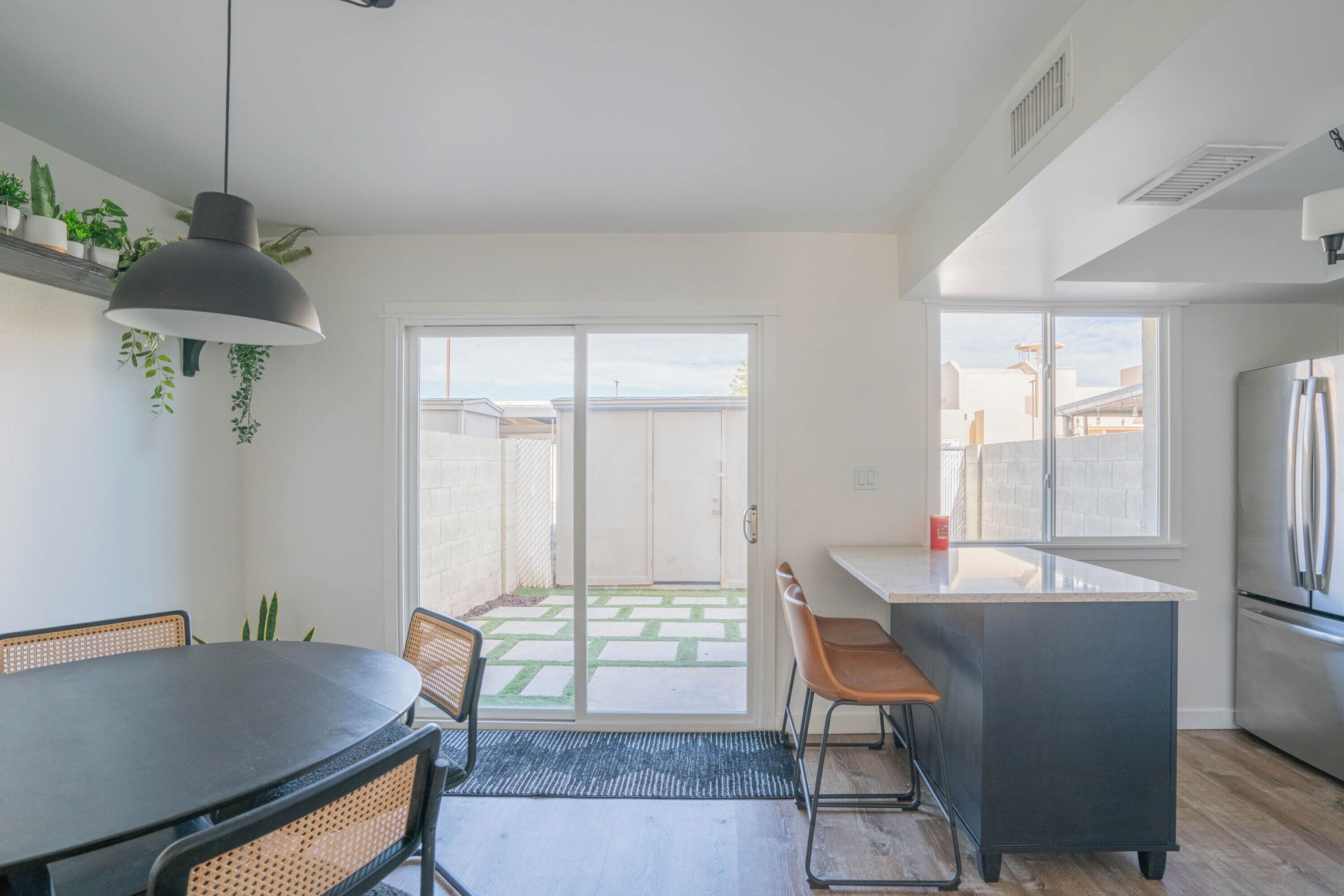 A modern kitchen with a dining area, a large window, and a view of the backyard.