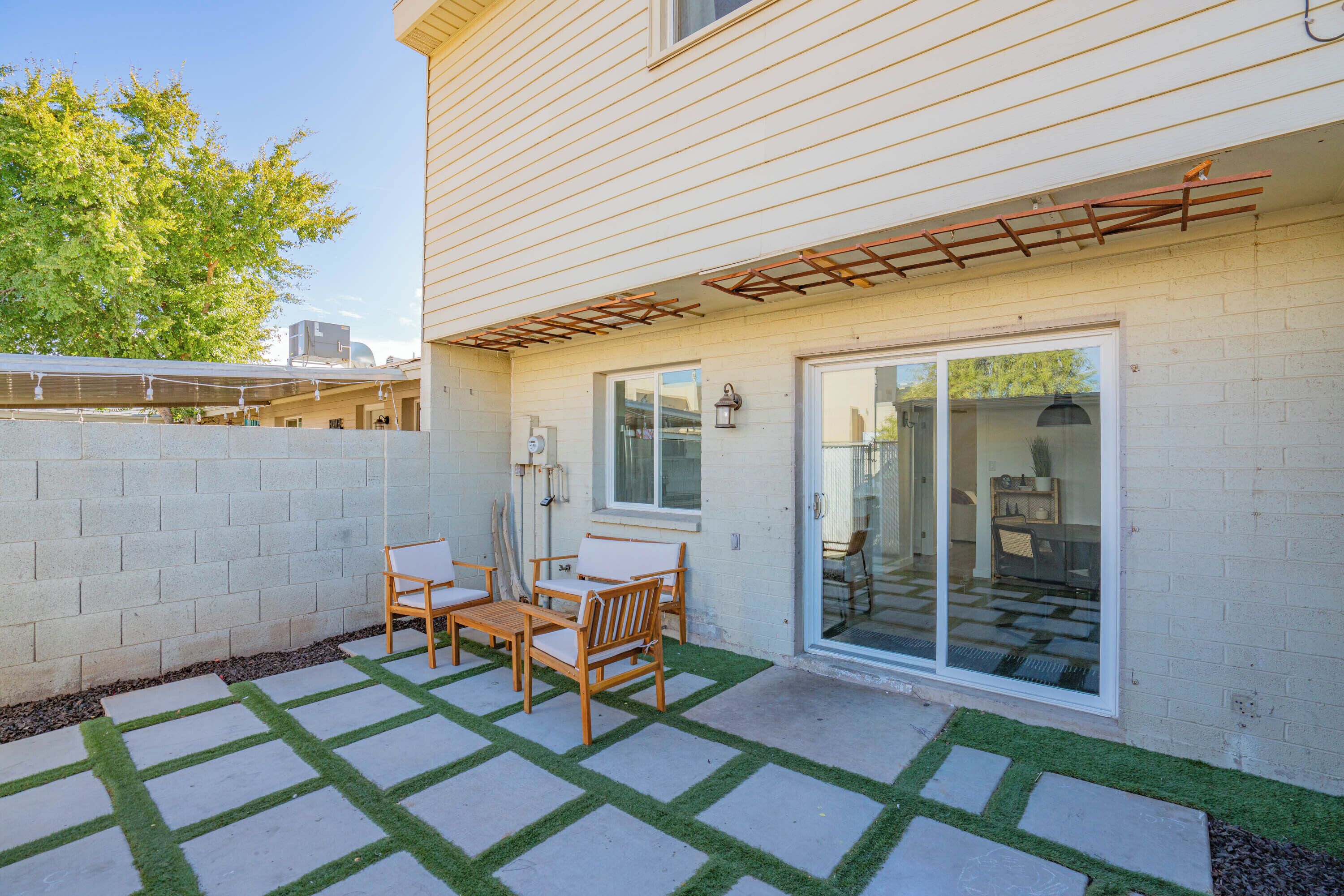 A patio with a table and chairs, a pergola, and a sliding glass door leading to an interior space.