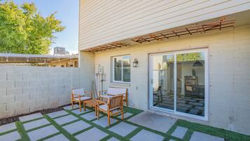 A patio with a table and chairs, a pergola, and a sliding glass door leading to an interior space.
