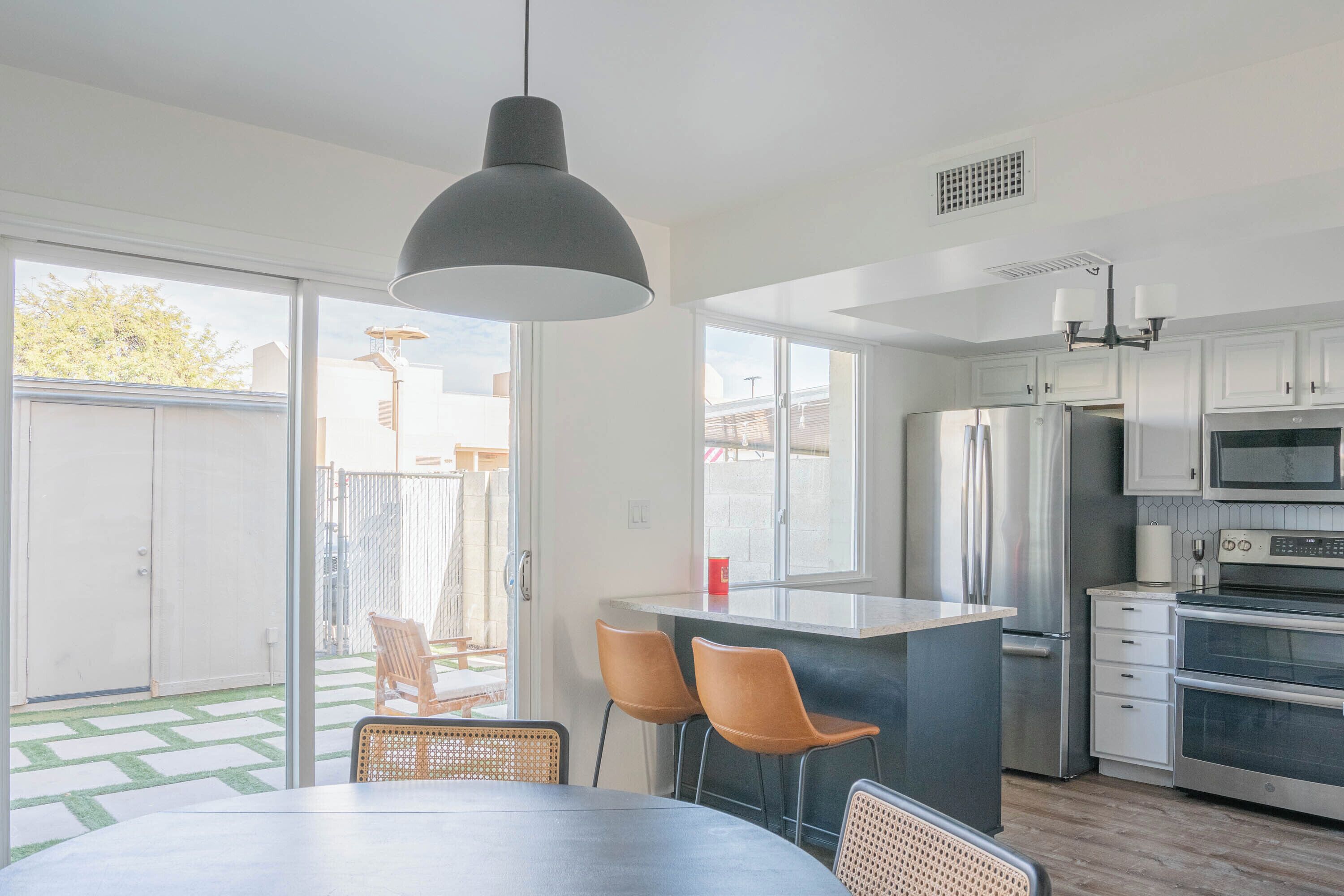 A modern kitchen with a large island, stainless steel appliances, and a dining area with chairs.