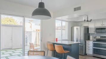 A modern kitchen with a large island, stainless steel appliances, and a dining area with chairs.