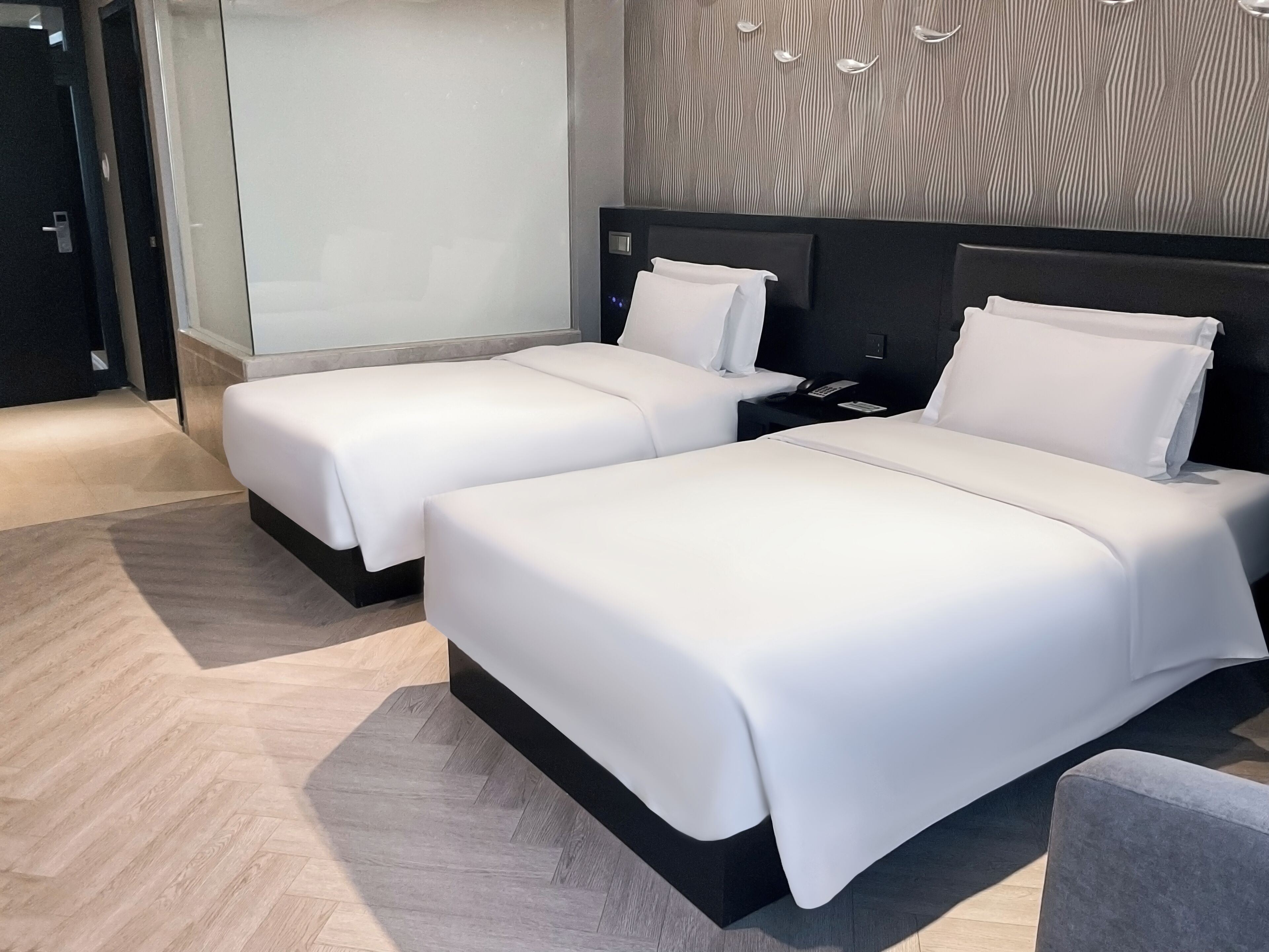 Une chambre d’hôtel avec deux lits, une table de chevet avec un téléphone et un décor mural moderne.