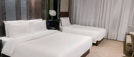 Habitación de hotel con una cama grande, una mesita de noche, un espejo, una silla y vistas a la ciudad.