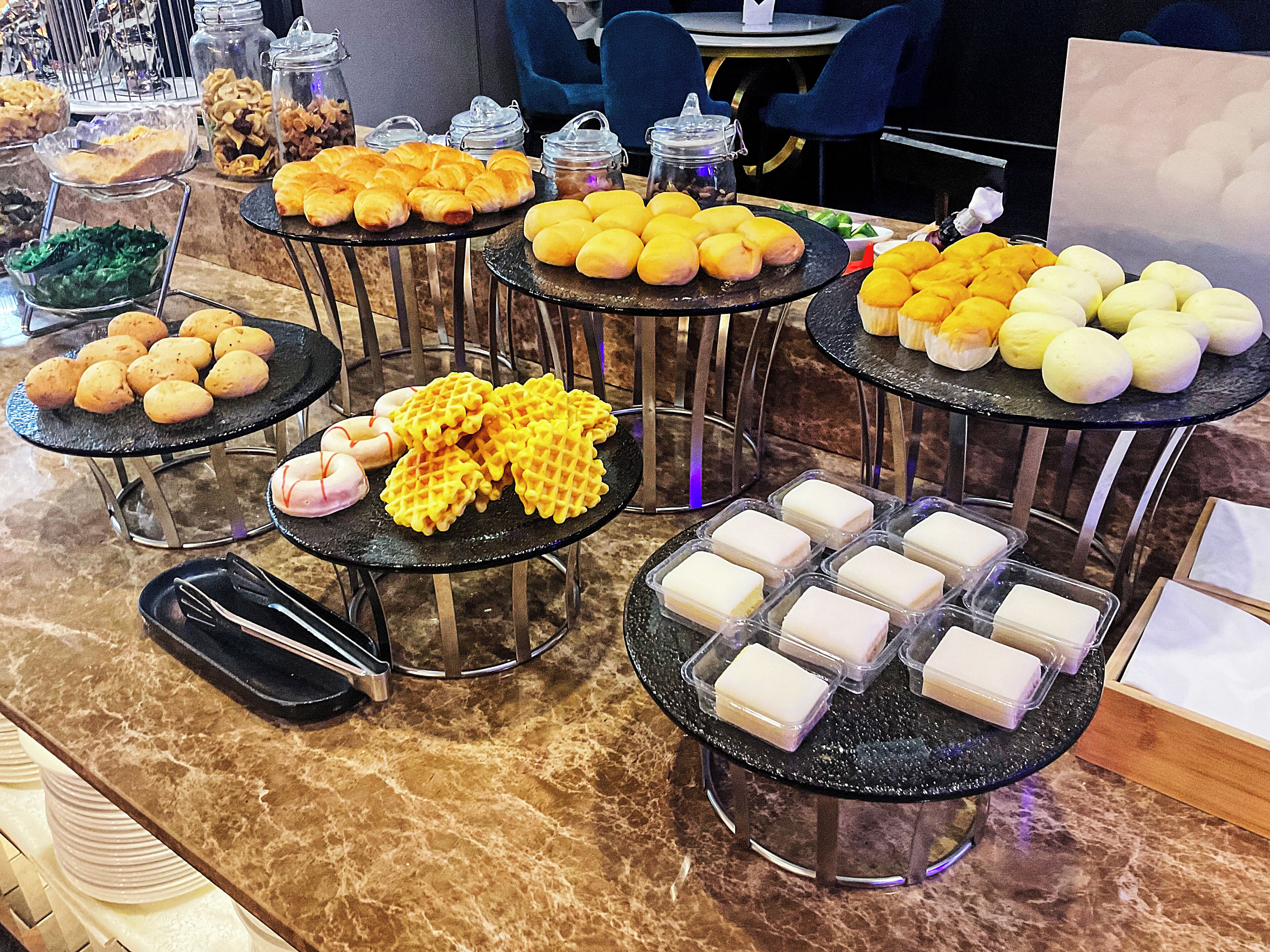 A buffet with various food items on multiple round tables.