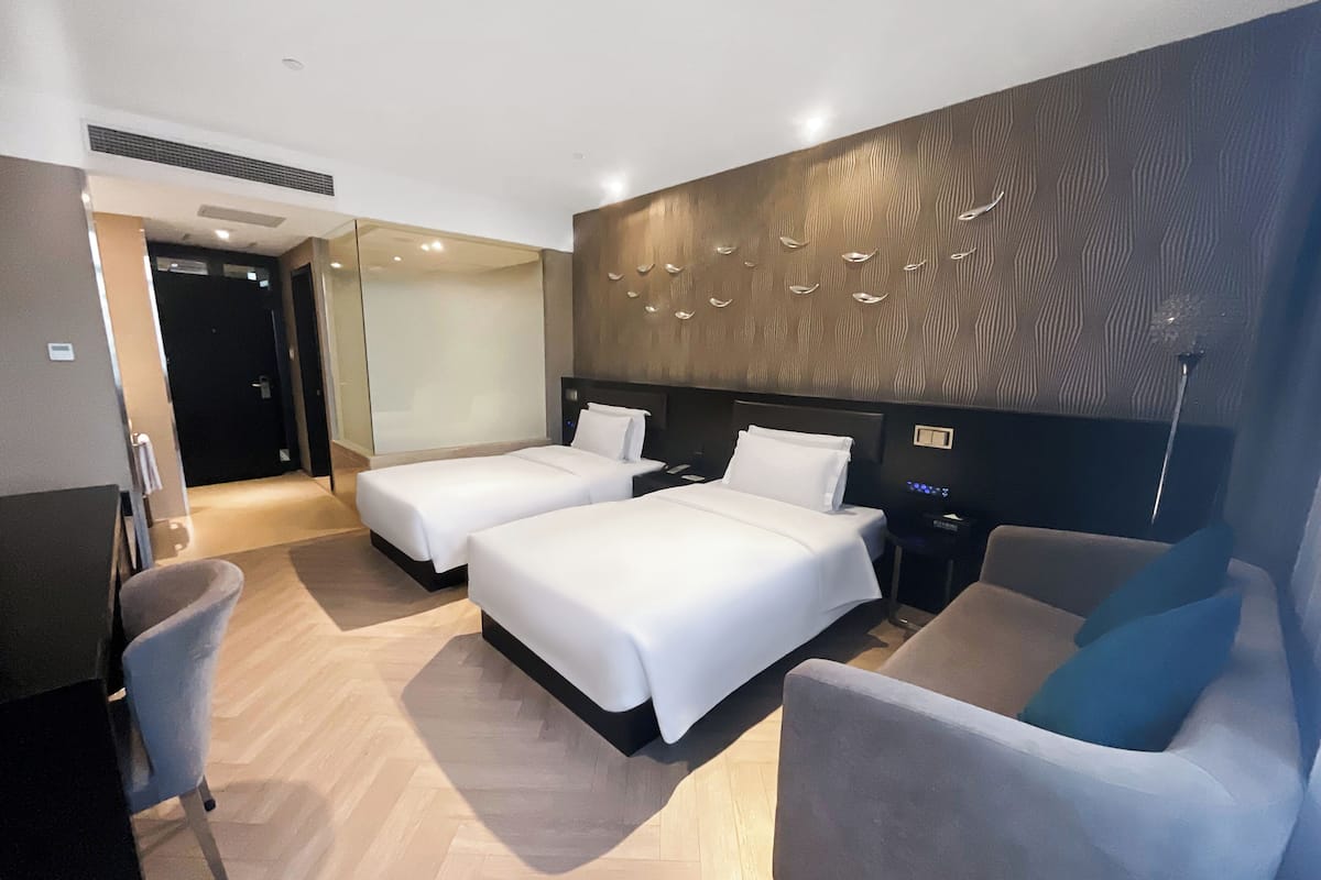 Una habitación de hotel con dos camas, un sofá, un escritorio y un espejo.