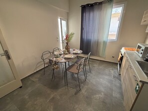 A compact kitchen with a dining area, a microwave, and a small window with a curtain. - Coral Urbanite (Rodos)