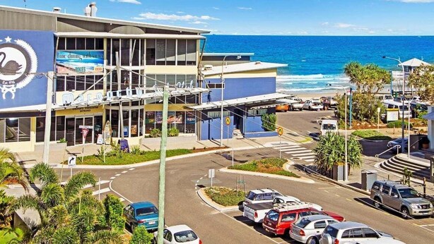A coastal building with a swan logo, a restaurant sign, and a view of the ocean. - 7 Coral Seas 35-37 Sixth Avenue (Maroochydore)