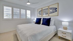 A bedroom with a bed, a nightstand, a lamp, and artwork on the wall. - 7 Coral Seas 35-37 Sixth Avenue (Maroochydore)
