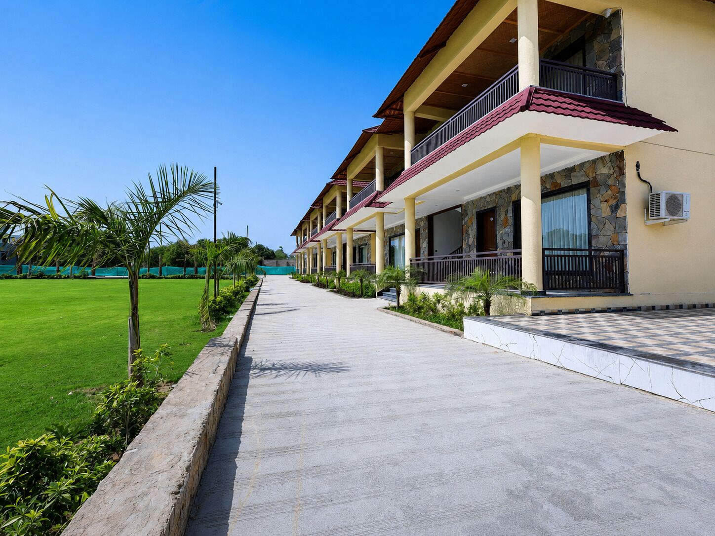 A hotel with a covered walkway, stone facade, and multiple balconies.