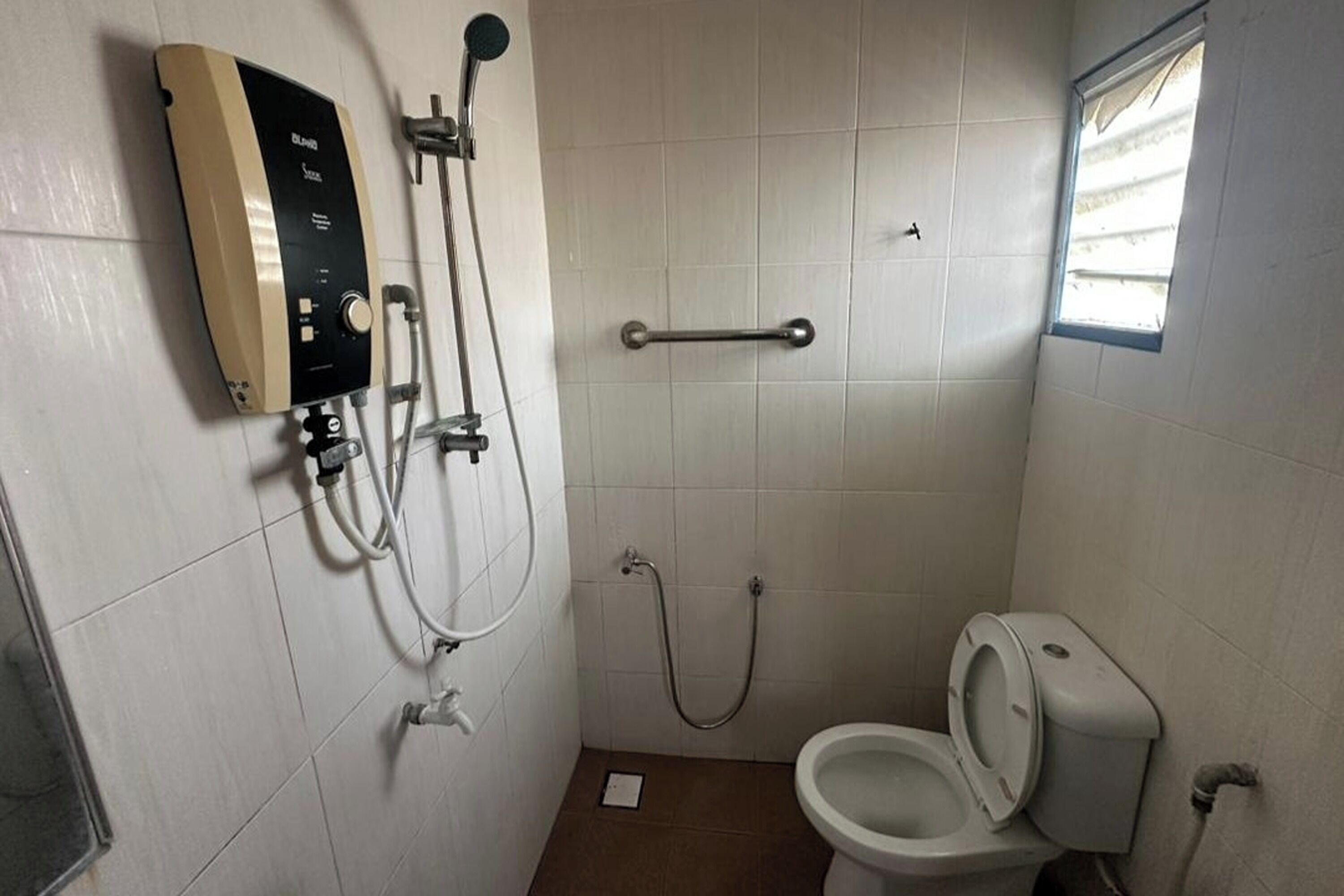 Un baño pequeño con inodoro, ducha y barra de apoyo.
