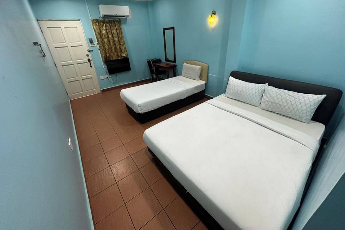 A room with two beds, a desk, a chair, a mirror, and a door.