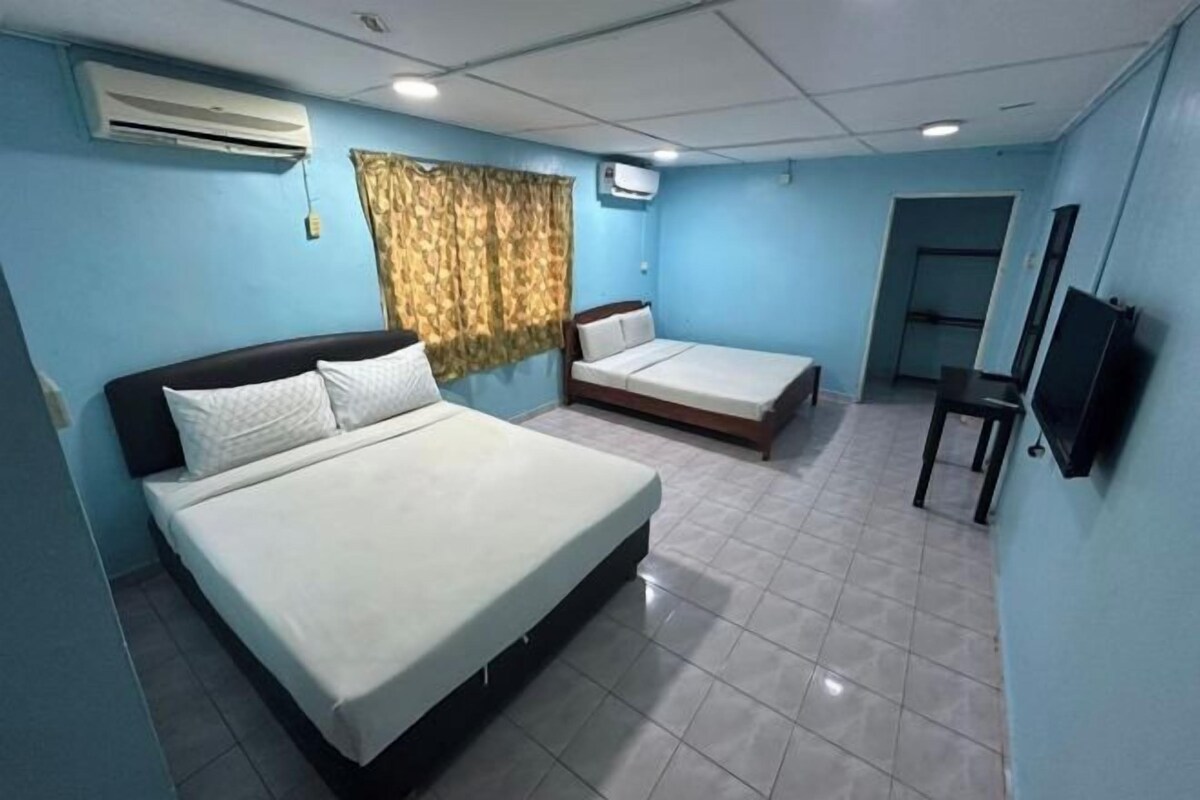 Una habitación de hotel con una cama grande, una cama más pequeña, un televisor y una ventana con cortinas.