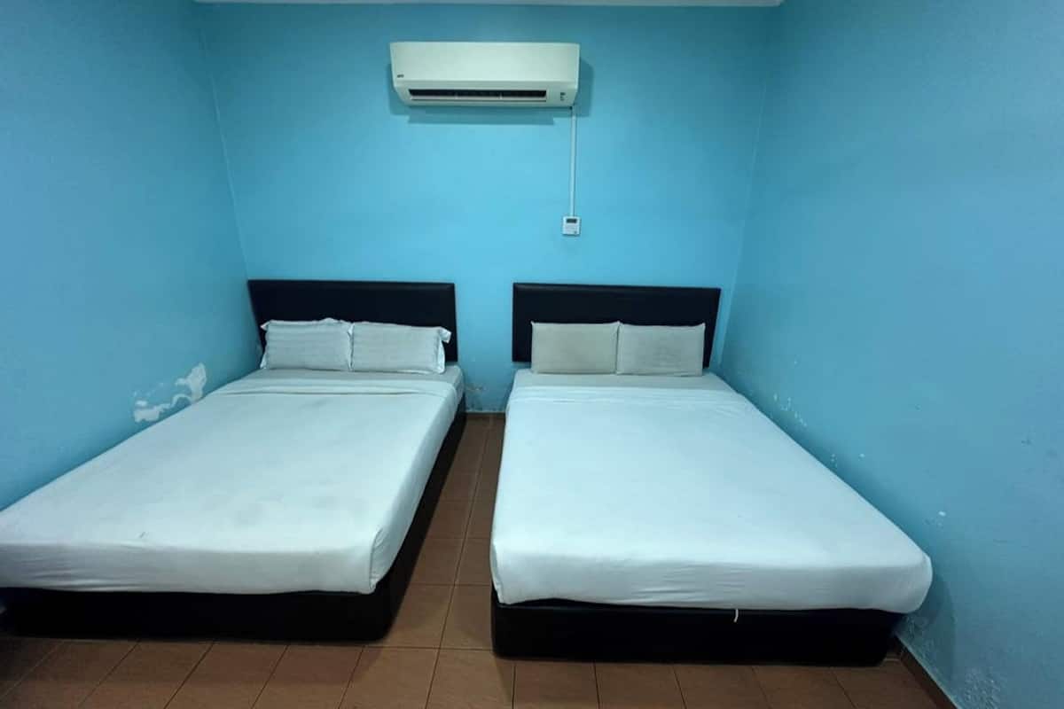 A room with two beds, a wall-mounted air conditioner, and a tiled floor.
