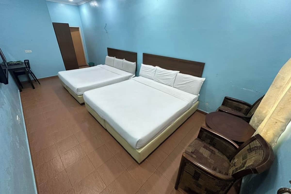 A room with two beds, a small table, and a chair.