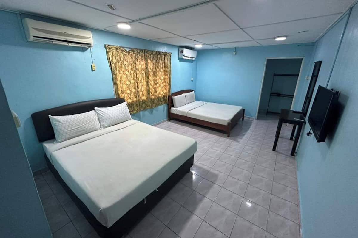 A hotel room with two beds, a TV, and an air conditioning unit.