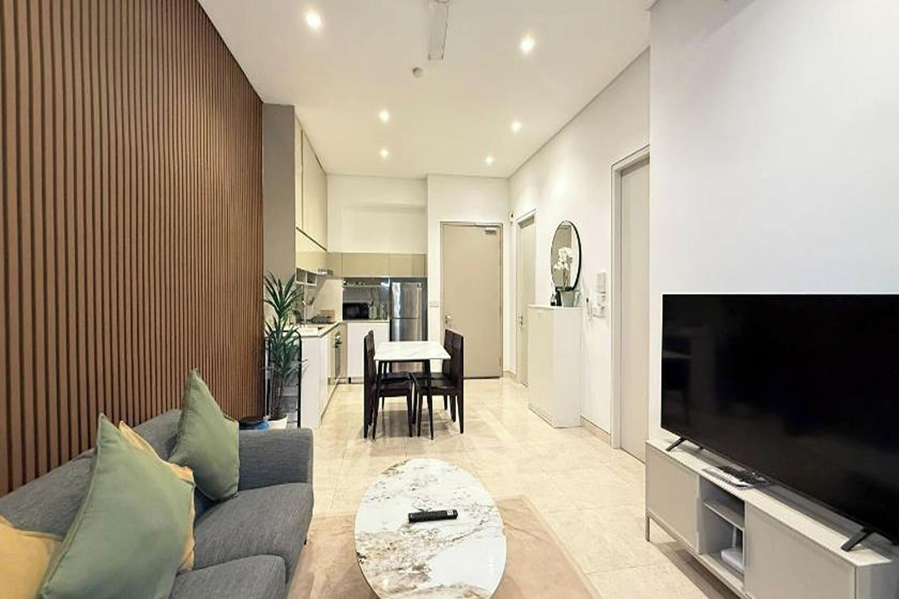 Un salon moderne comprenant un canapé, une table basse, un téléviseur et un coin repas avec des chaises et une table.