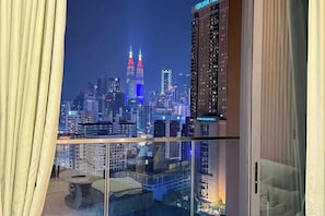 A high-rise hotel room with a city view, large windows, and a glass table. - Lucentia Residence Bukit Bintang Lalaportbbcc By Vellora (Kuala Lumpur)