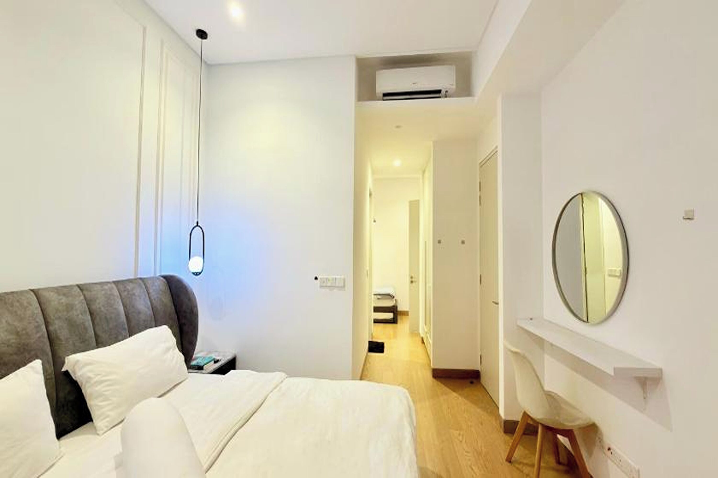 Une chambre à coucher avec un lit, une table de chevet et un miroir au mur.