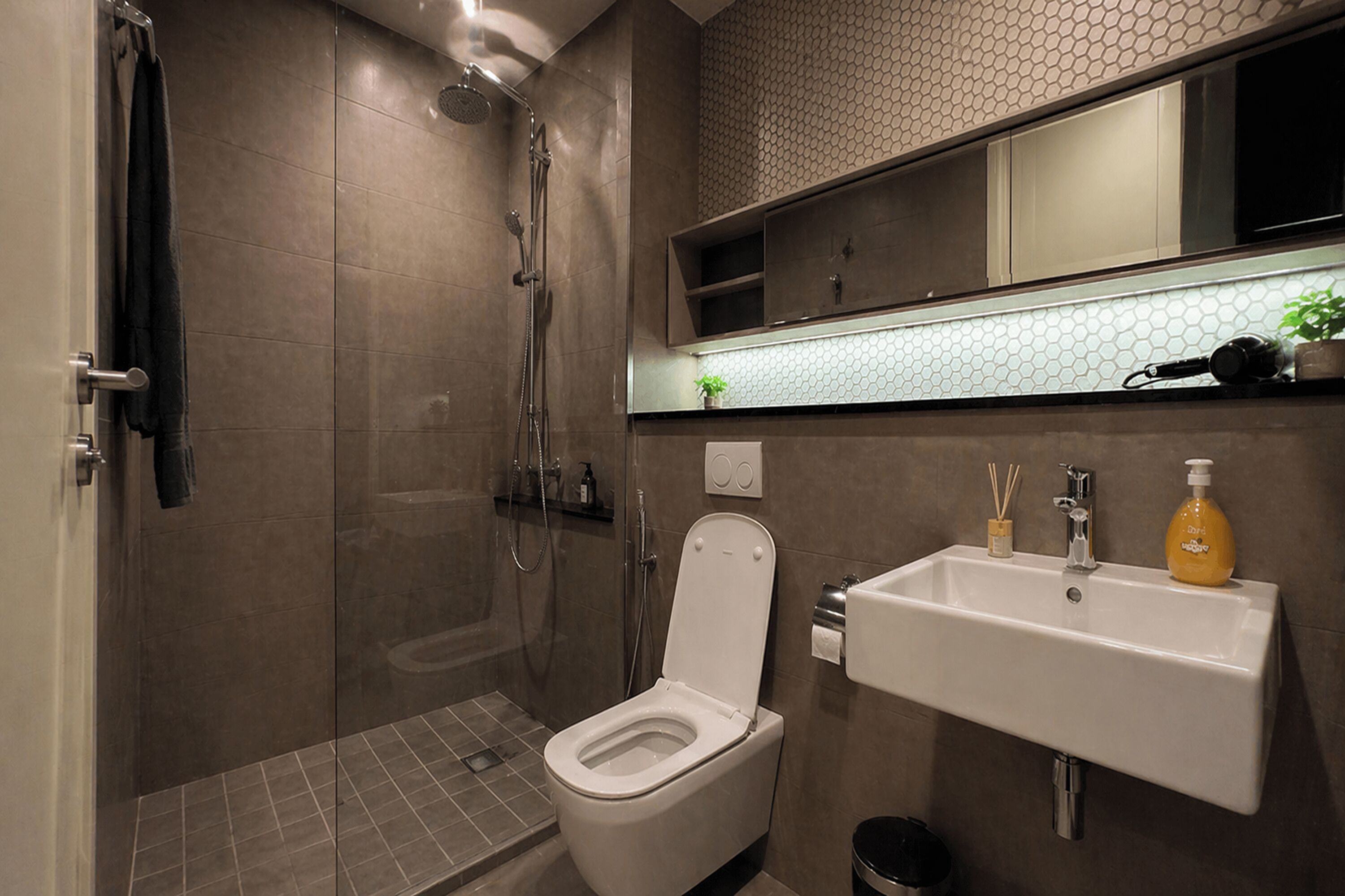 Une salle de bain moderne équipée d’une douche, de toilettes, d’un lavabo et d’un miroir au-dessus du lavabo.