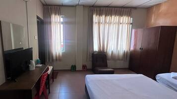 Una habitación de hotel con una cama, un escritorio, una silla, un armario y cortinas.