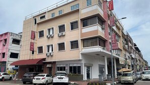 Un hotel de varios pisos con fachada plana, unidades de aire acondicionado y una entrada visible.