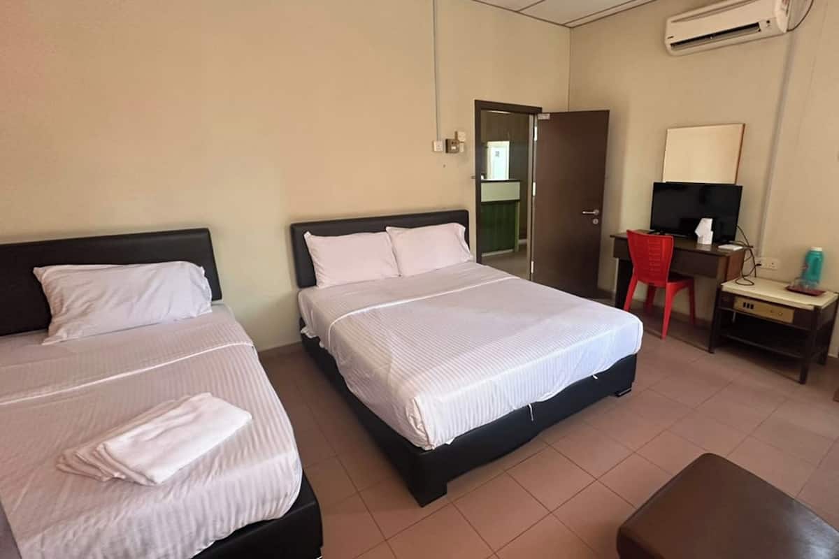 A hotel room with two beds, a desk with a chair, a TV, and an air conditioning unit.