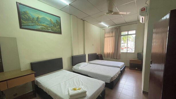Una habitación de hotel con dos camas, un escritorio, un cuadro en la pared y una ventana con cortinas.