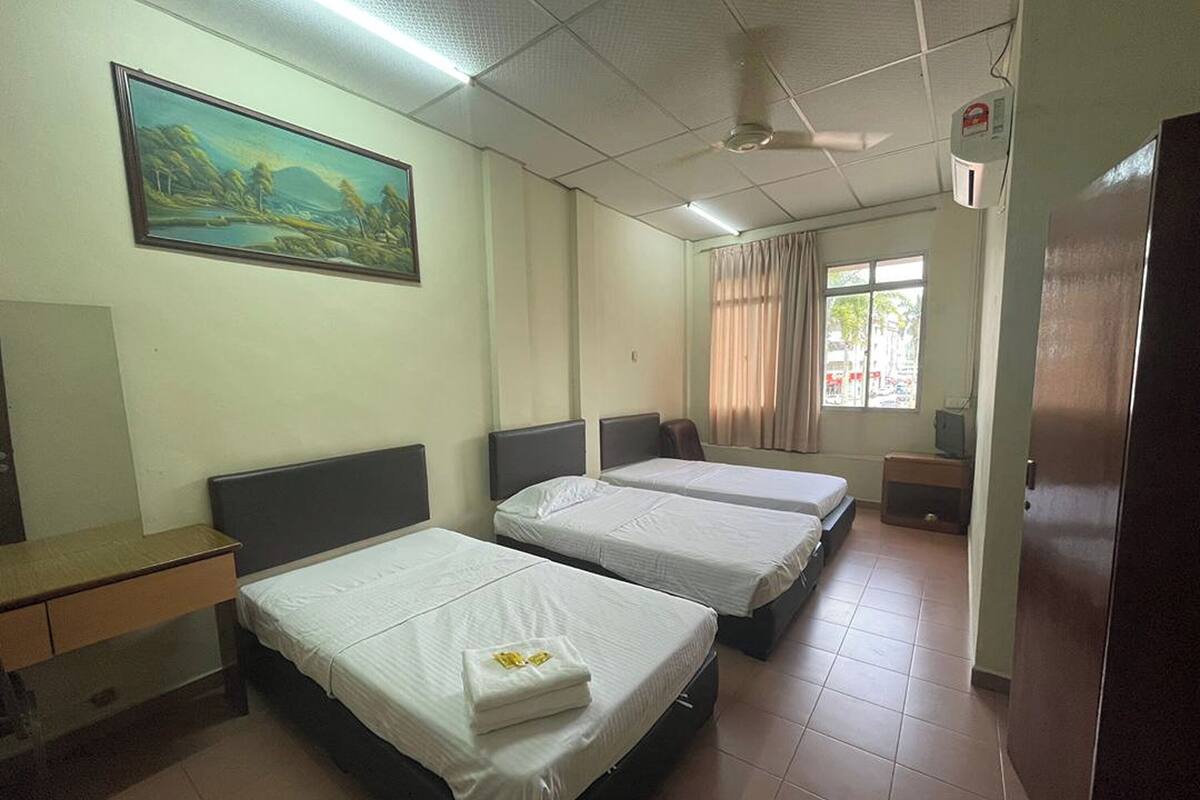 A hotel room with two beds, a desk, a painting on the wall, and a window with curtains.
