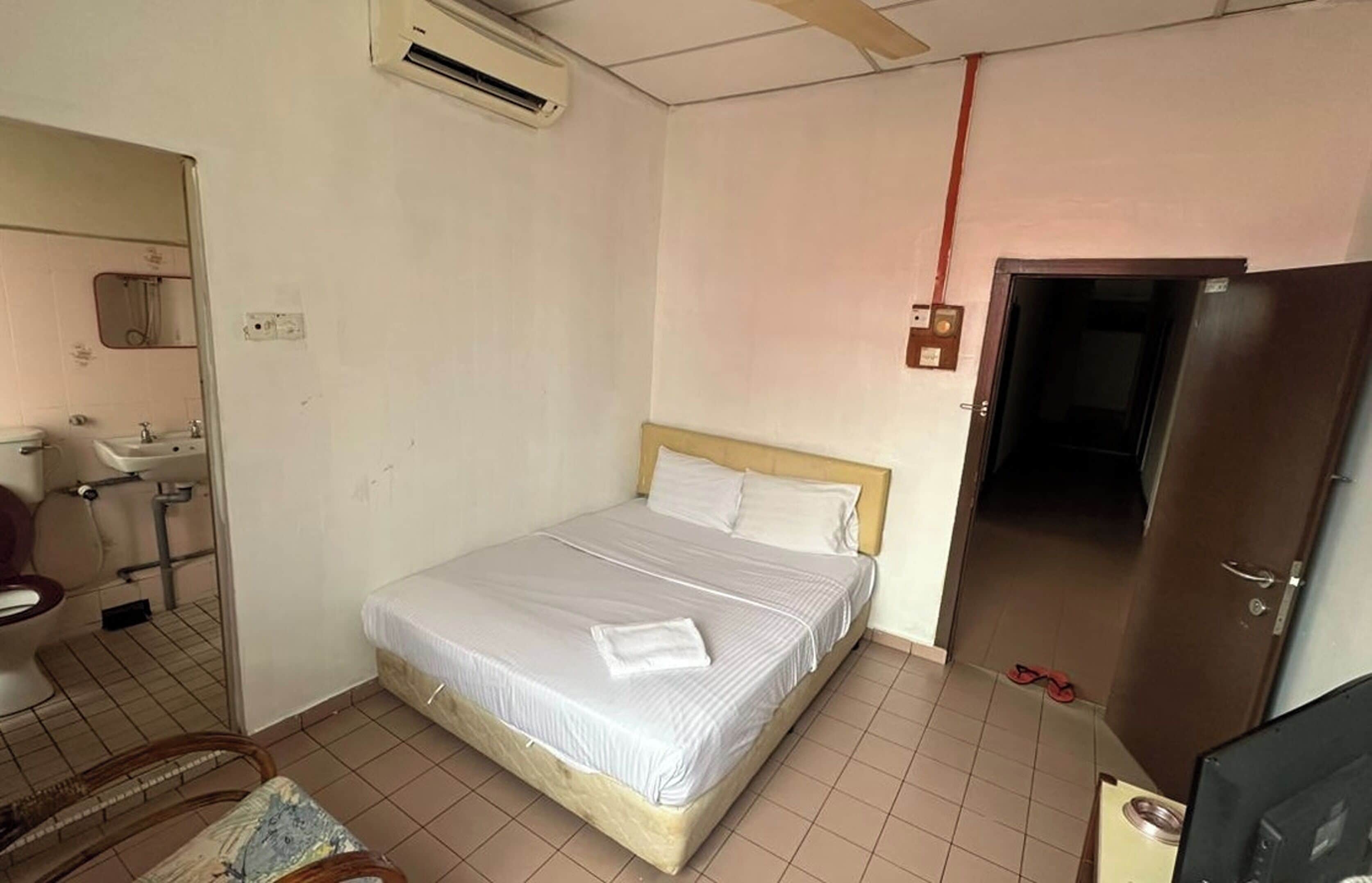 A bedroom with a bed, a mirror, a sink, and a door.