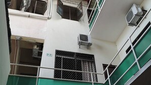 Un edificio de varios pisos con una decoración verde y blanca, unidades de aire acondicionado y una barandilla de metal.