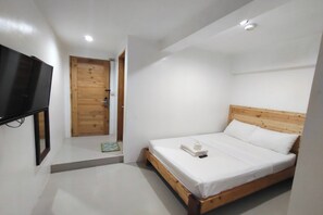 Quarto com cama de madeira, televisão de tela plana na parede e porta de madeira.