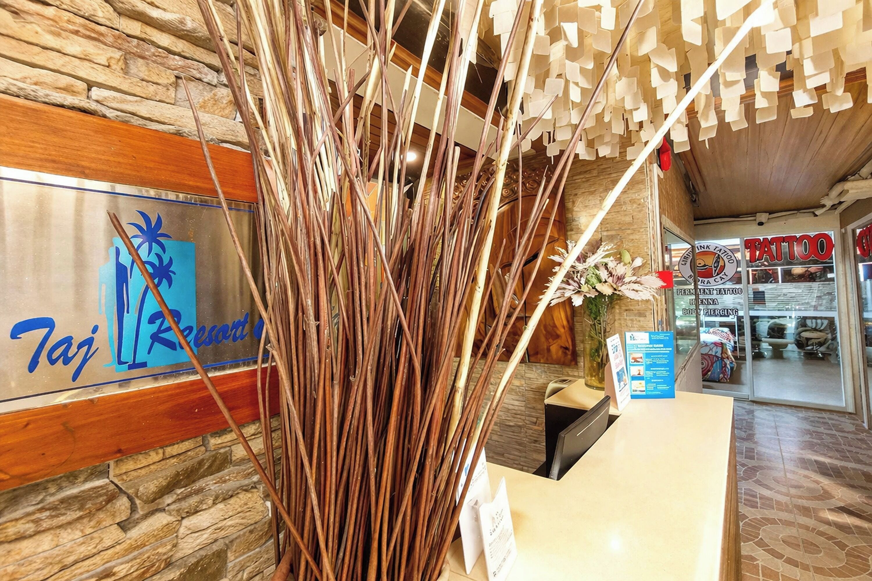 A reception desk with a sign for 'Taj Resort' and a visible tattoo parlor.