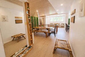 A modern interior with a wooden dining table, benches, and a plant wall. - Taj Resort And Spa (Boracay Island)