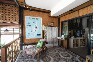Una habitación con pared de bambú, un mapa, una silla de mimbre, una mesita y un armario.