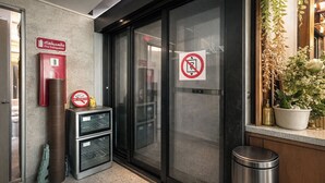 A hotel entrance with a fire extinguisher, a no smoking sign, and a trash bin. - Nonoteru Chiang Mai Kamphaeng Din (Chiang Mai)