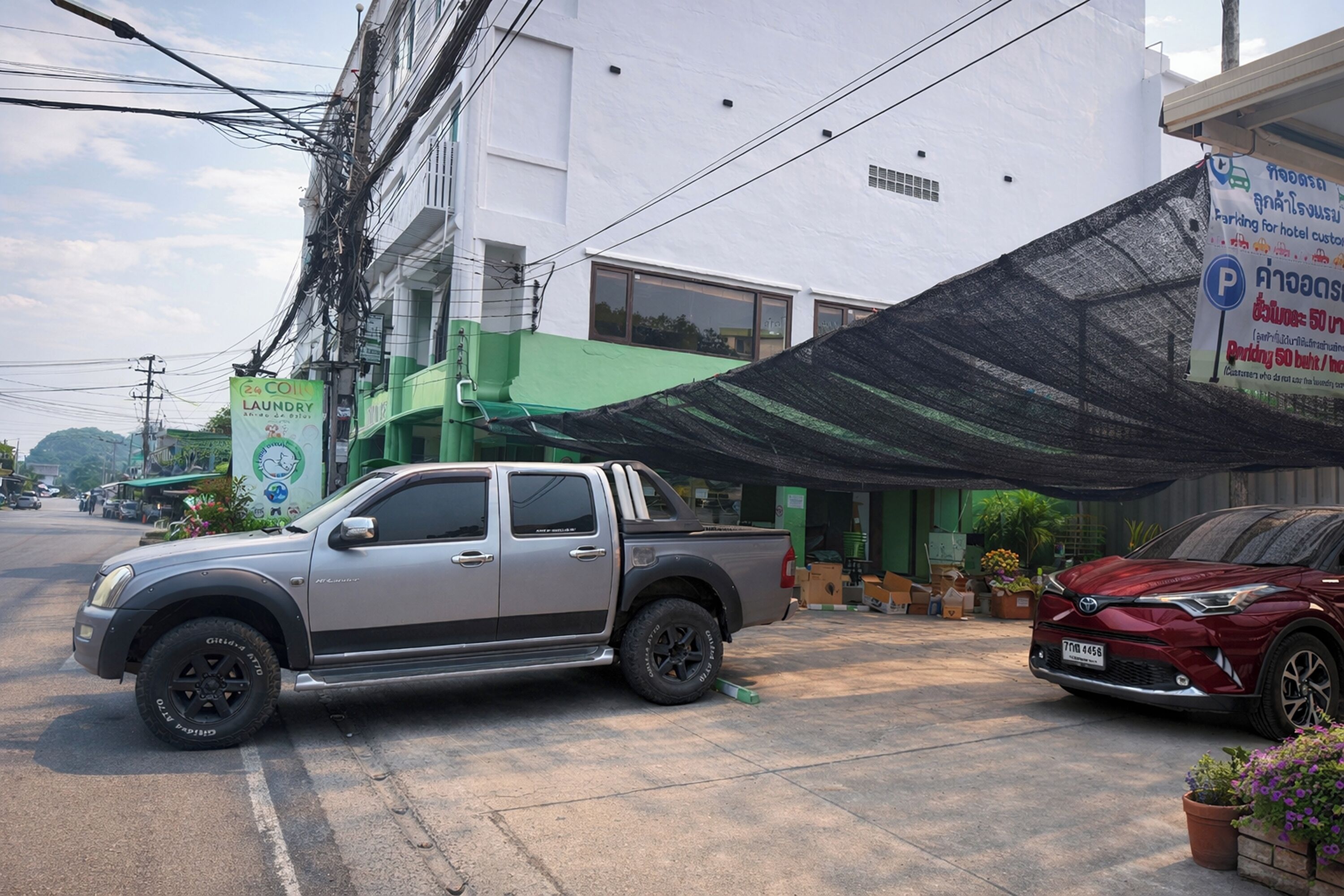 A silver pickup truck parked in front of a building with a green awning and a sign for a laundry service.