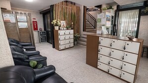 A reception area with a counter, a seating area with black leather chairs, a bamboo wall, and a staircase. - Nonoteru Chiang Mai Kamphaeng Din (Chiang Mai)