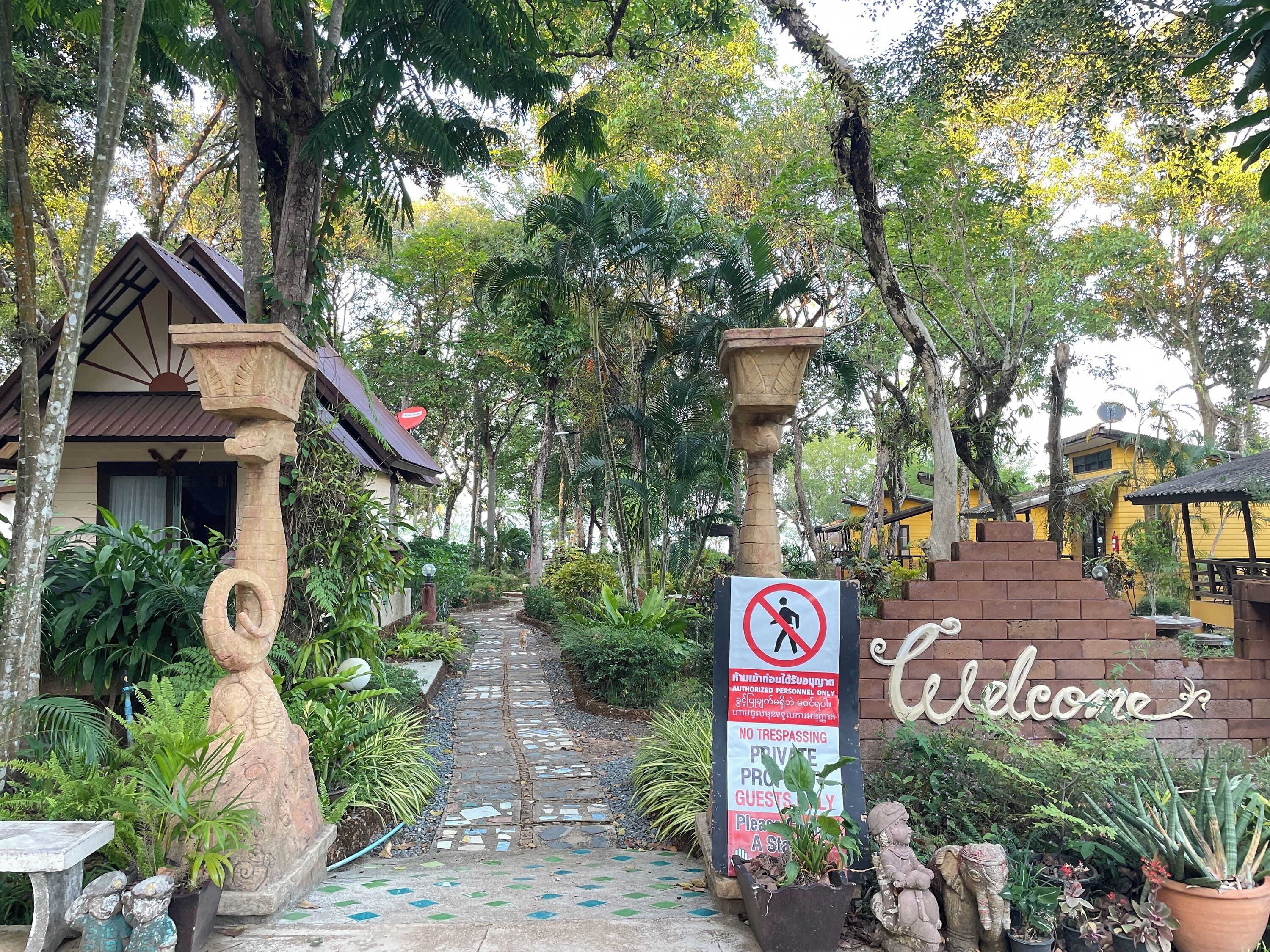Entrada privada con letrero de 'prohibido el paso', cartel de bienvenida y un camino de piedra que conduce a un edificio.
