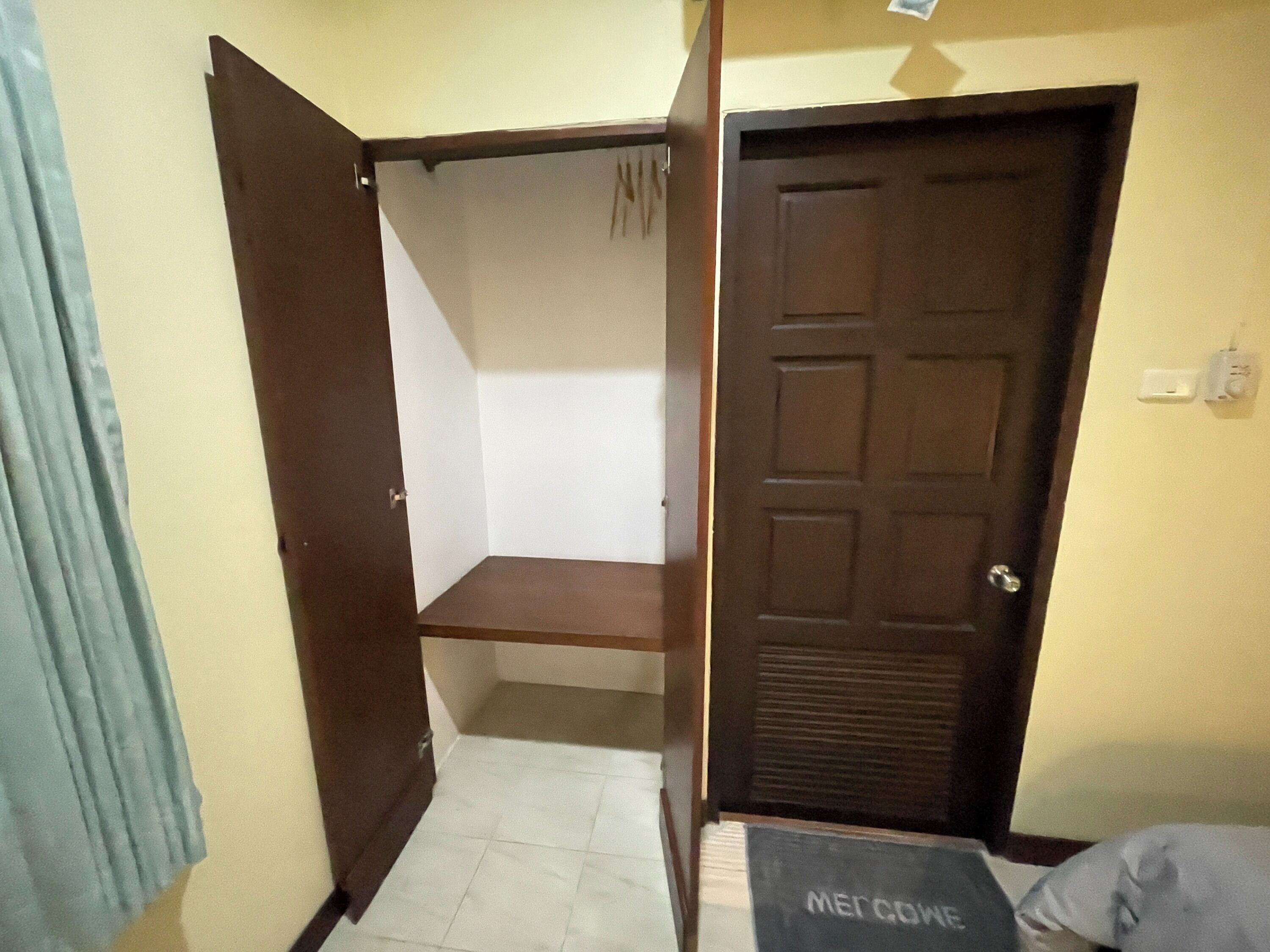 Una stanza con una porta chiusa, un armadio e un letto con materasso a vista.