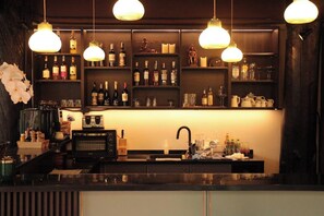Un espace bar avec des étagères remplies de bouteilles, une machine à café et un évier.