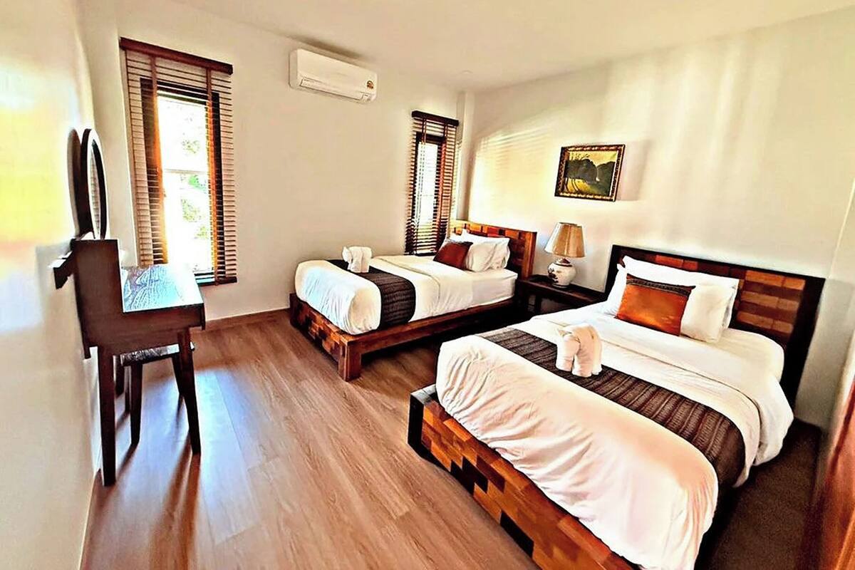 A hotel room with two beds, a desk, and a chair.