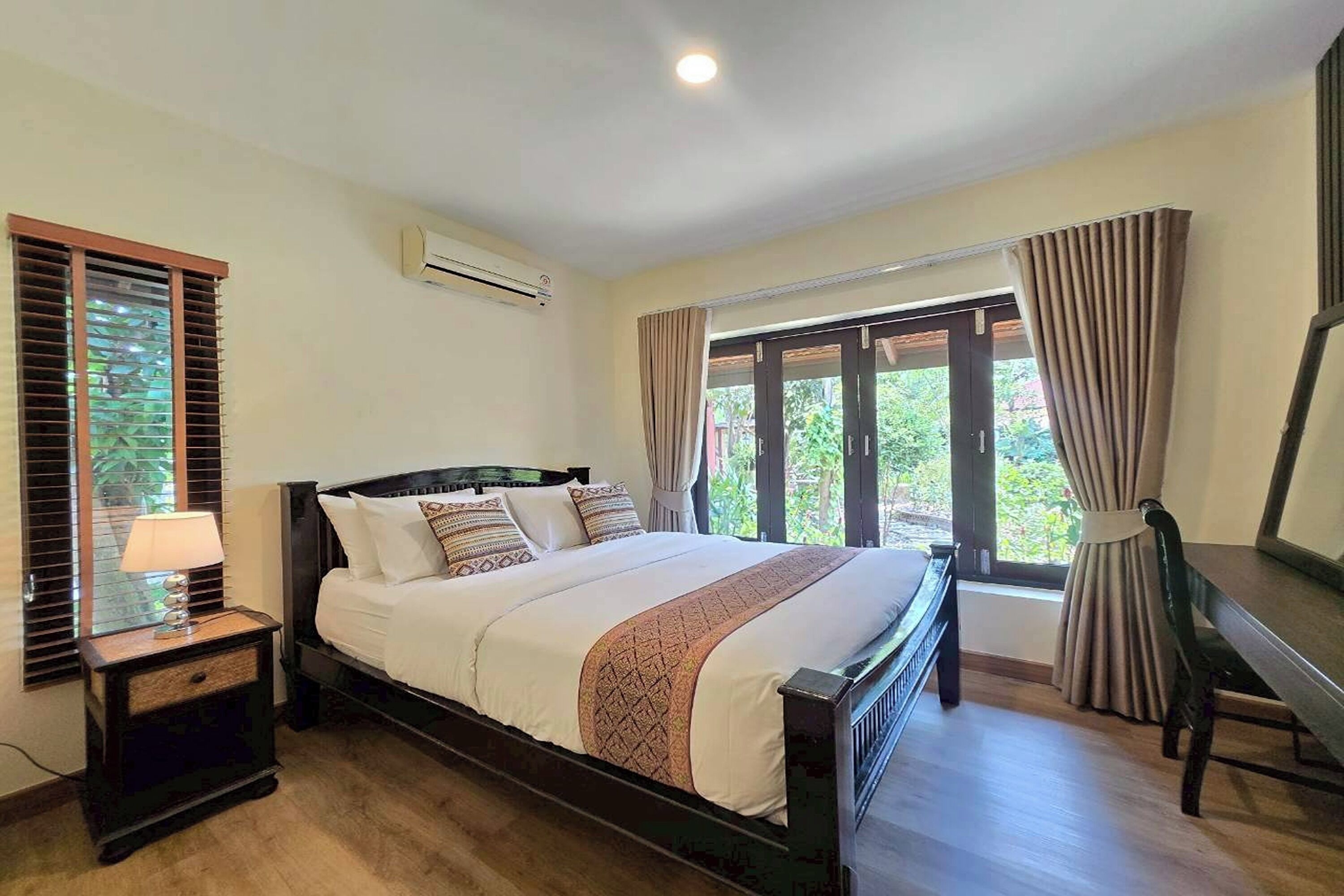 A bedroom with a bed, nightstand, and a desk.