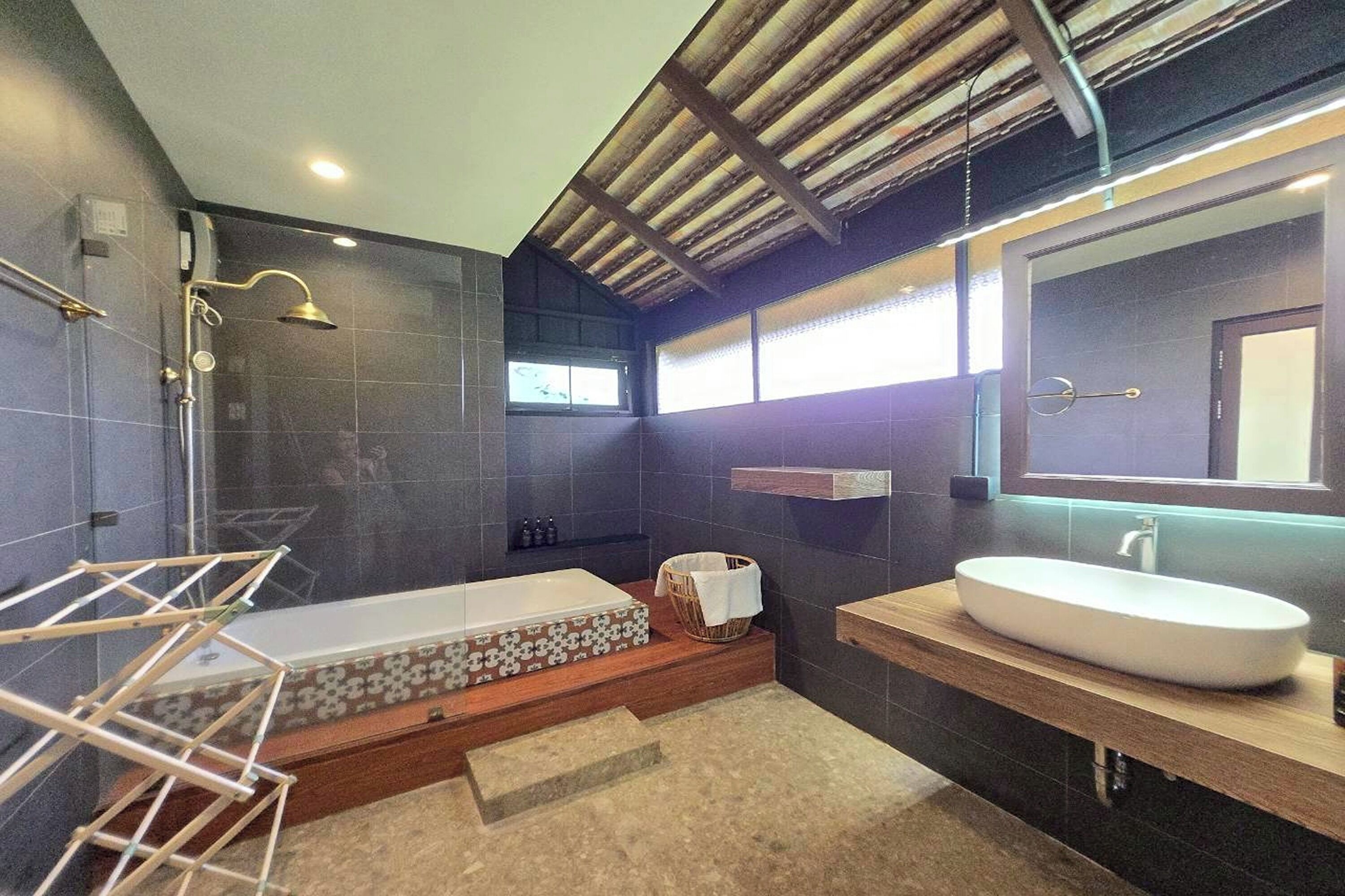 A modern bathroom with a bathtub, a large mirror, and a shower area.