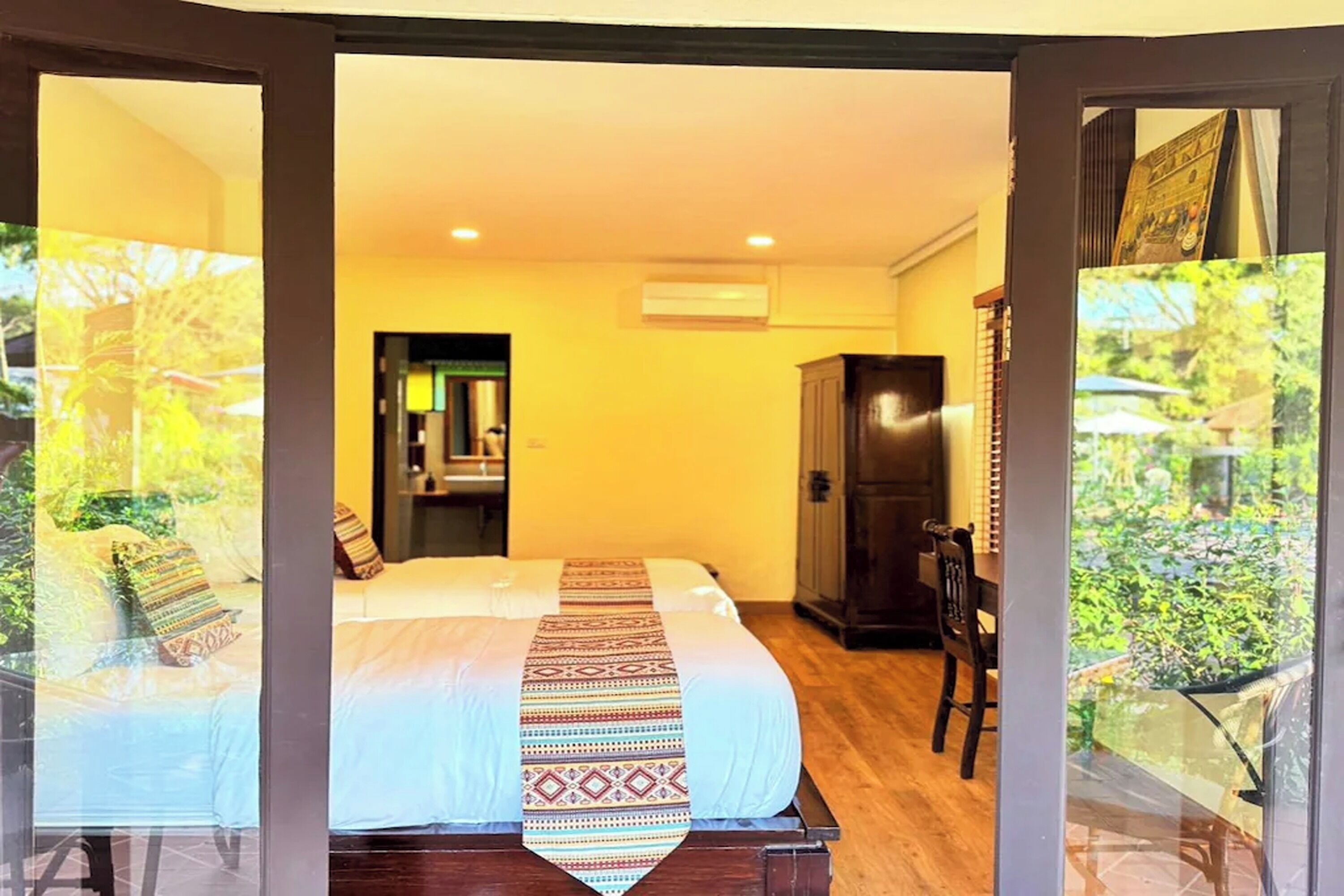 Une chambre avec un lit, une armoire et une vue sur l’extérieur, visible à travers une porte vitrée.