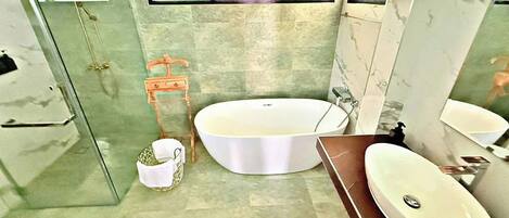 Une salle de bain avec une baignoire sur pieds, un lavabo séparé et un espace douche.