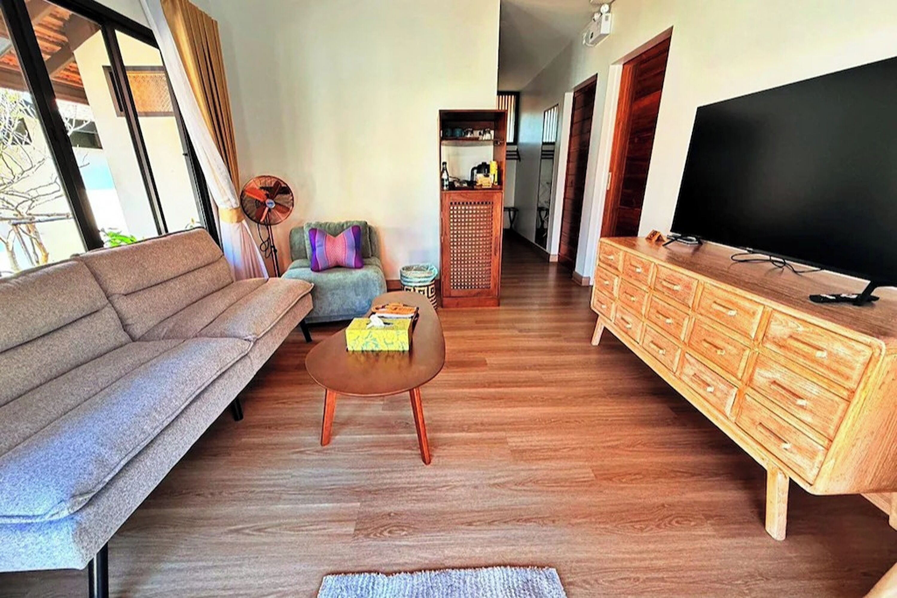 A living room with a sofa, a coffee table, a TV, and a wooden cabinet.